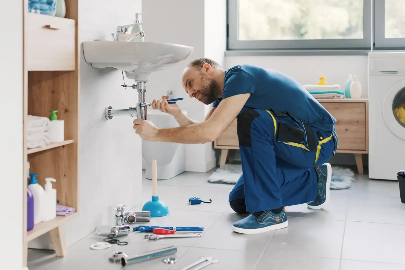 Plumber working under a bathroom sink. Illustrative photograph.