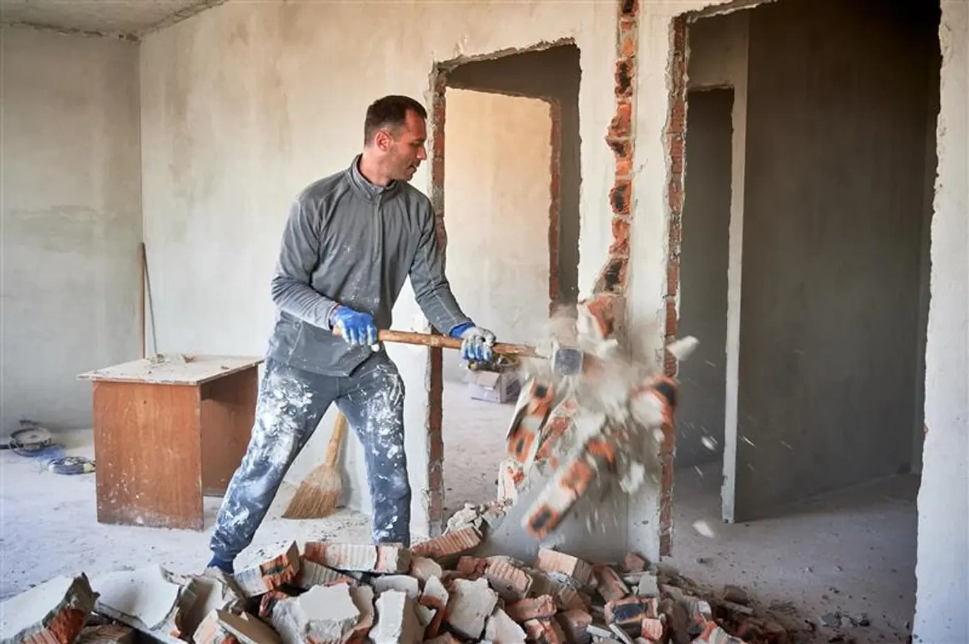 Tradesperson demolishing an interior wall. Illustrative photograph.